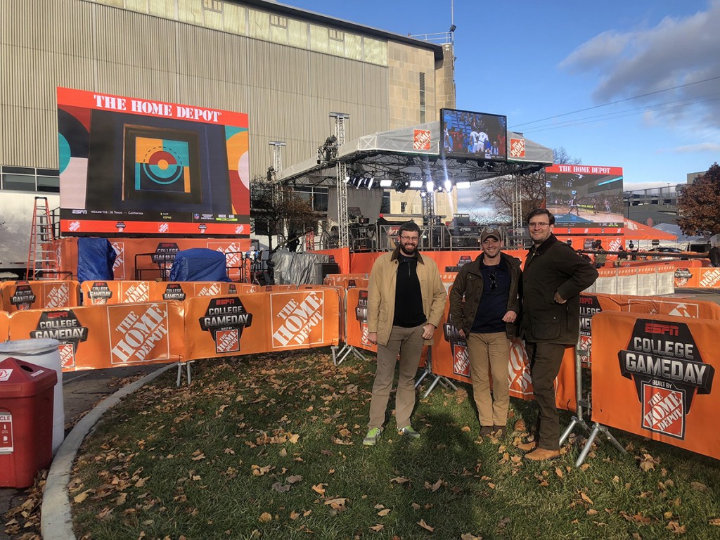 Christopher, Zachary, and Michael in front of the GameDay set as the crew sets up